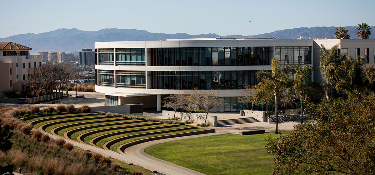 A view of Hannon library from a distance with Lawton Plaza in the foreground and mountains in the background.